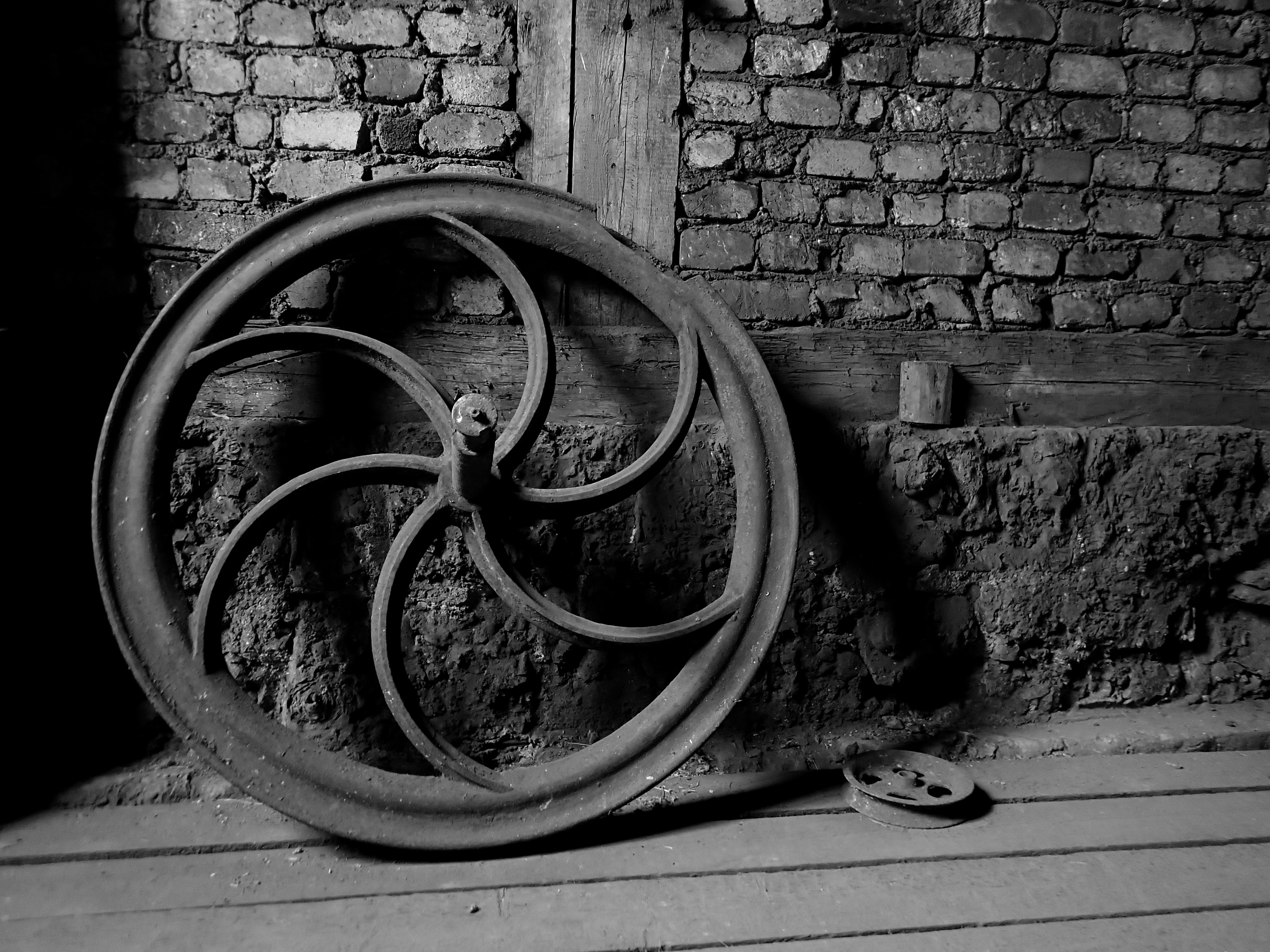 Old diecast wheel from unknown mining equipment, leaning against old brick wall.