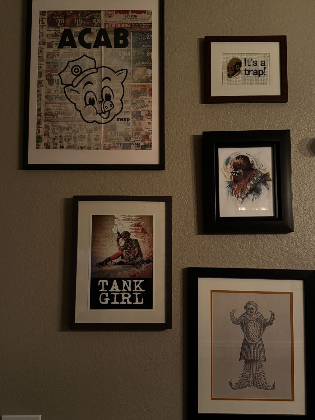 Multiple pieces of art - a print of the Piggly Wiggly mascot with a police hat and ACAB above it on a piggly wiggly flyer, a tank girl print, needlepoint “it’s a trap”, a Chewbacca print, and a surreal medieval print