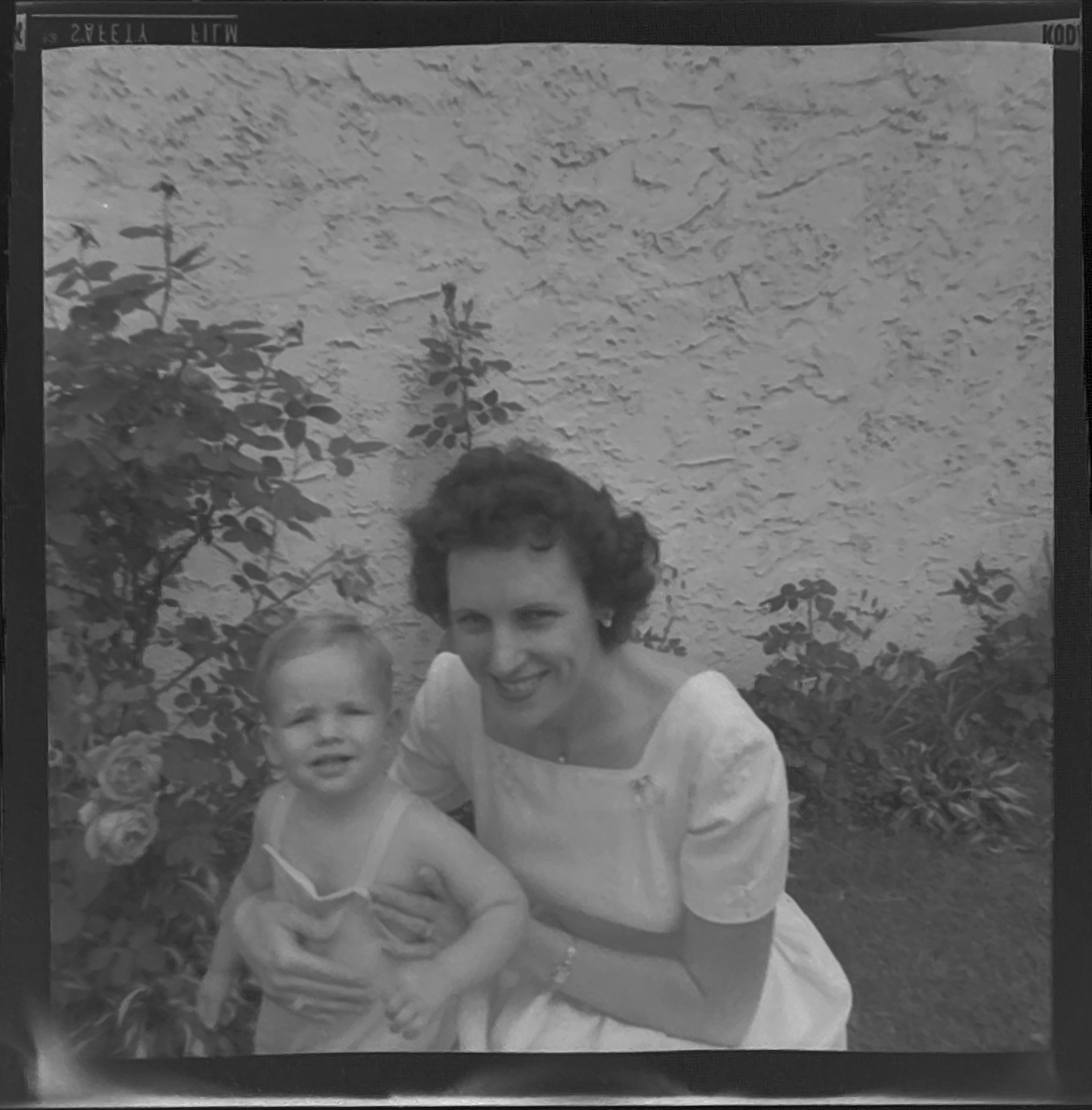 Black and white shot of a woman with a toddler. He's wearing a romper and no shirt, she's wearing a light-colored dress.