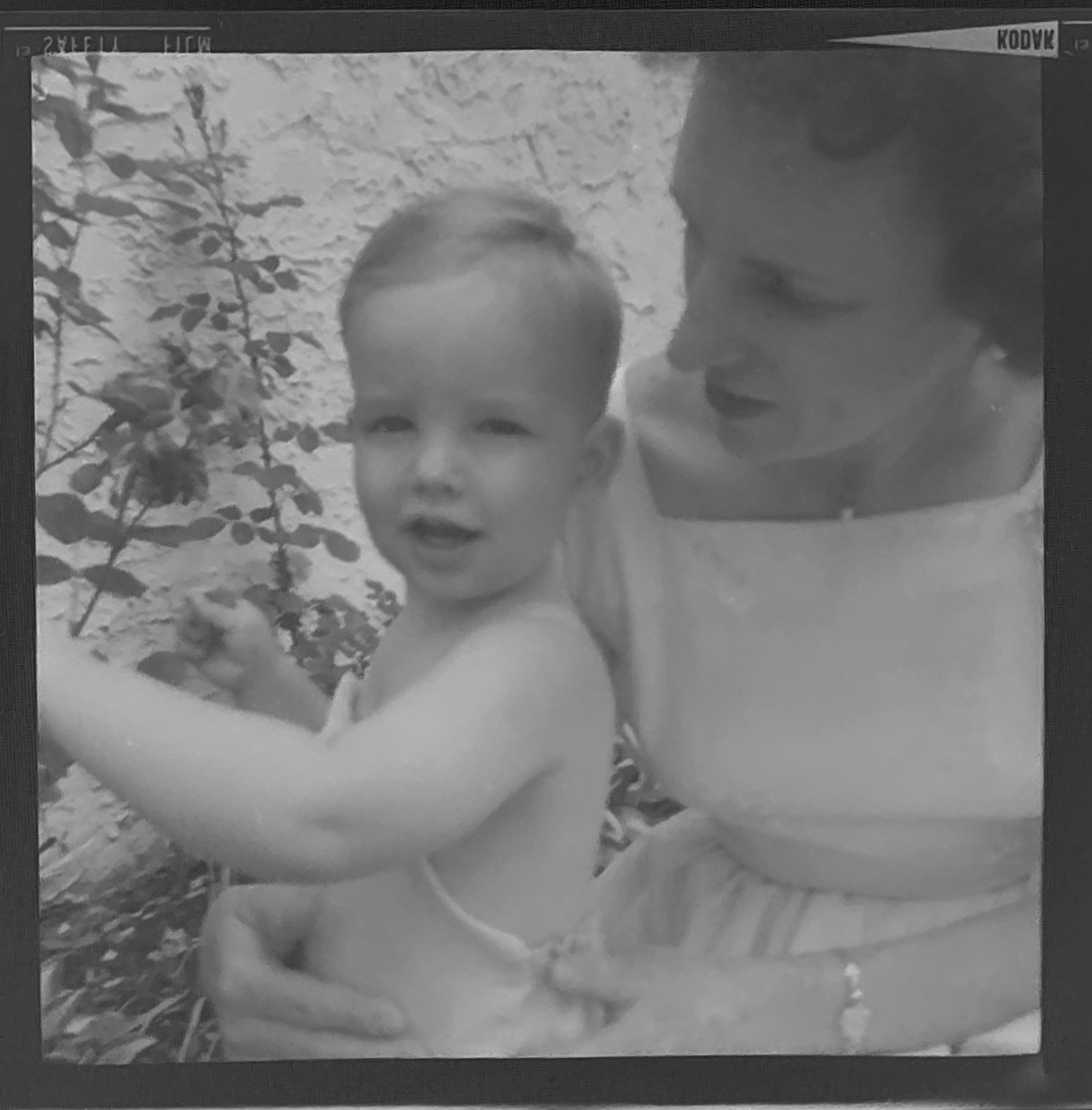 Black and white shot of a woman with a toddler. He's wearing a romper and no shirt, she's wearing a light-colored dress.