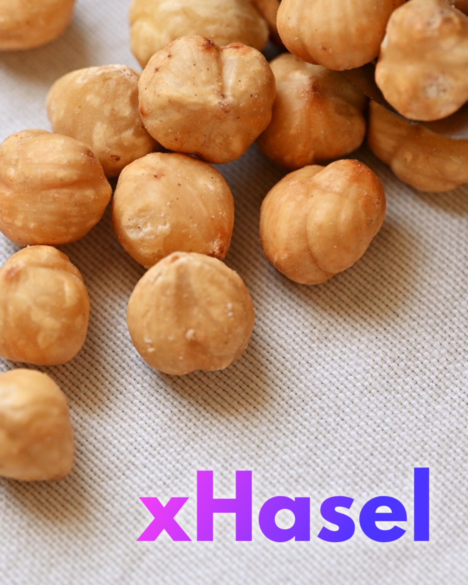 Mehrere geschälte Haselnüsse liegen locker auf einem hellen, leicht strukturierten Stoffuntergrund. Einige Nüsse sind scharf fokussiert, andere liegen leicht unscharf im Hintergrund.