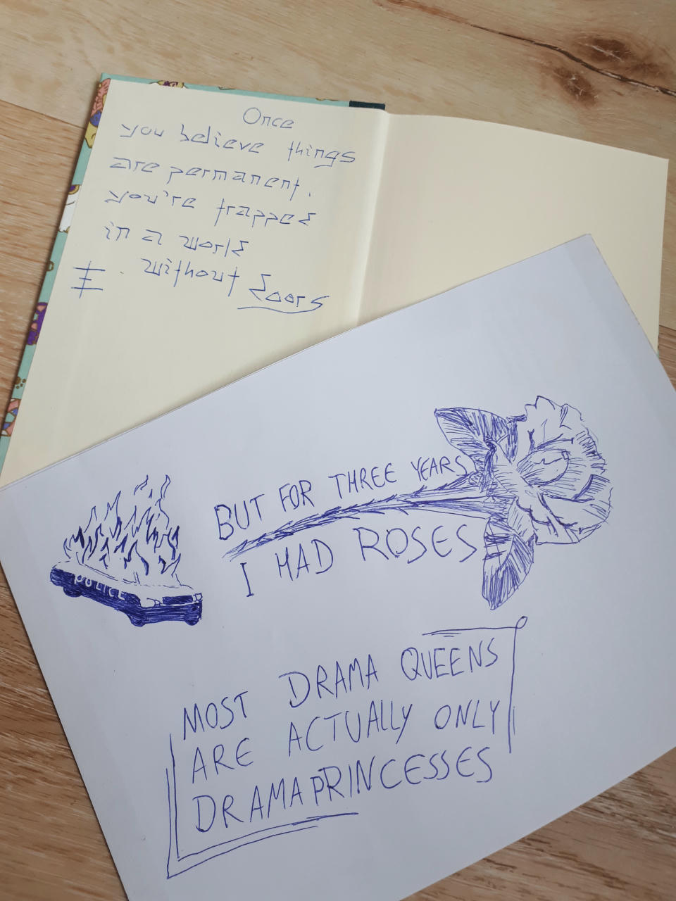 Skizzen von Tattoo-Ideen, darunter eine Rose mit dem Zitat "but for three years I had roses", der Satz "Most drama queens are actually only drama princesses", der Satz "Once you believe things are permanent, you're trapped in a world without doors", und ein brennendes Polizeiauto.