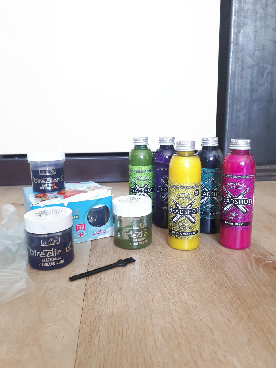 Einige Dosen bunte Haarfarben stehen beinander, in pink, schwarz, gelb, blau, dunkelgrün, und zwei weiteren dunklen Tönen.