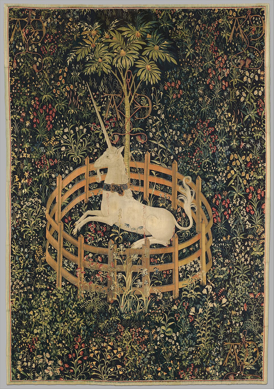 A unicorn in the centre of the picture. A fence is surrounding it and the background shows a dark green pasture with a tree and countless flowers