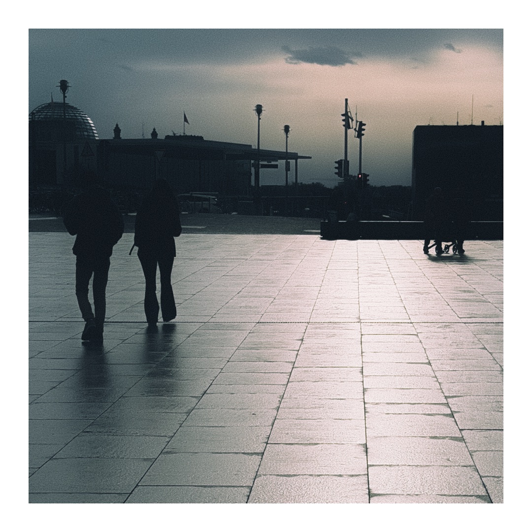 Nasser Platz im Gegenlicht mit Menschen und Schatten