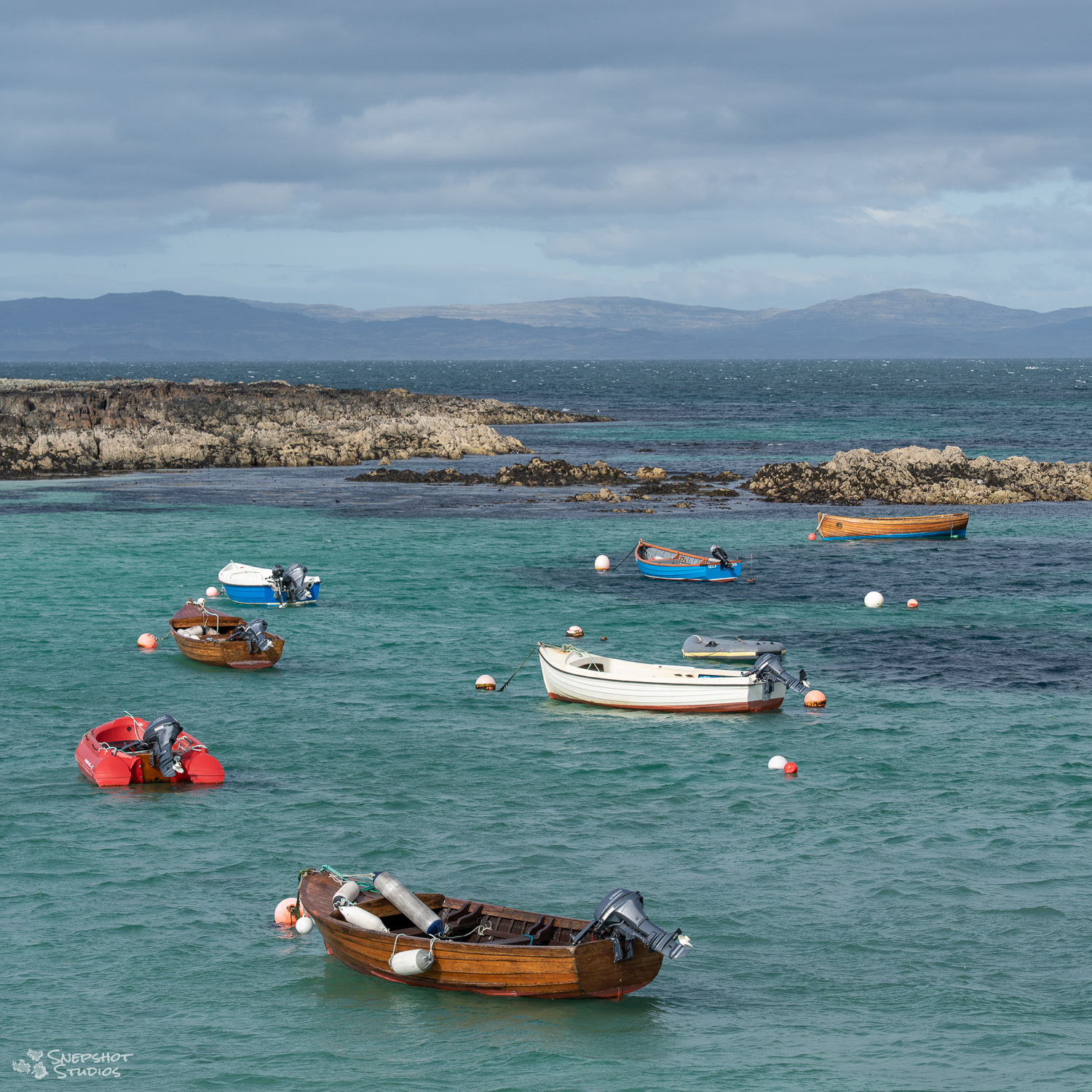 small, mainly wooden, boats in a harbor between rocks on the Scottish island of Iona