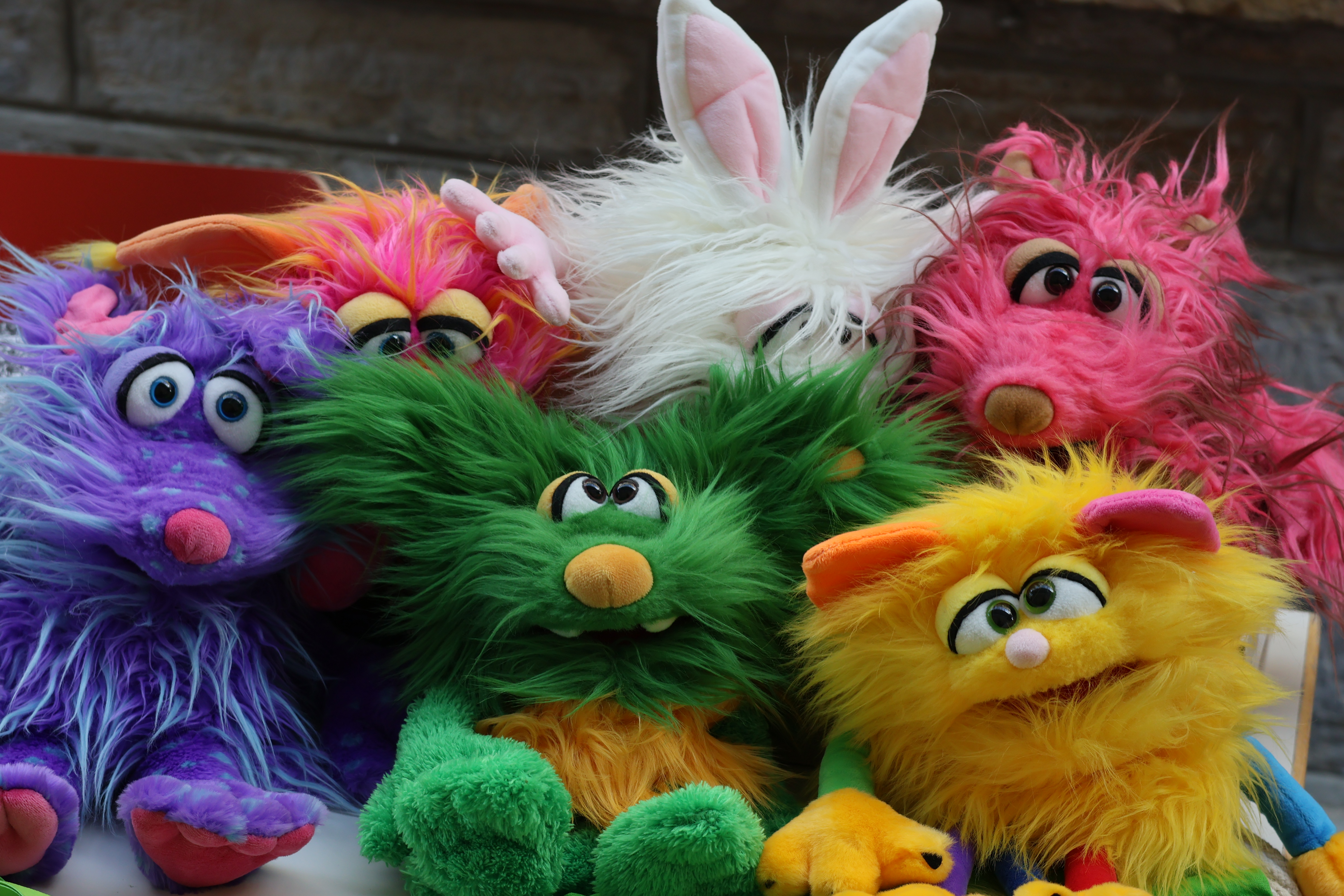 Fünf bunte Stofftiere mit plüschigem Fell nach Art der Muppets.