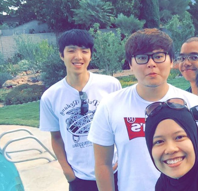 four individuals took a picture infront of a garden and a swimming pool at the very edge (left from bottom).