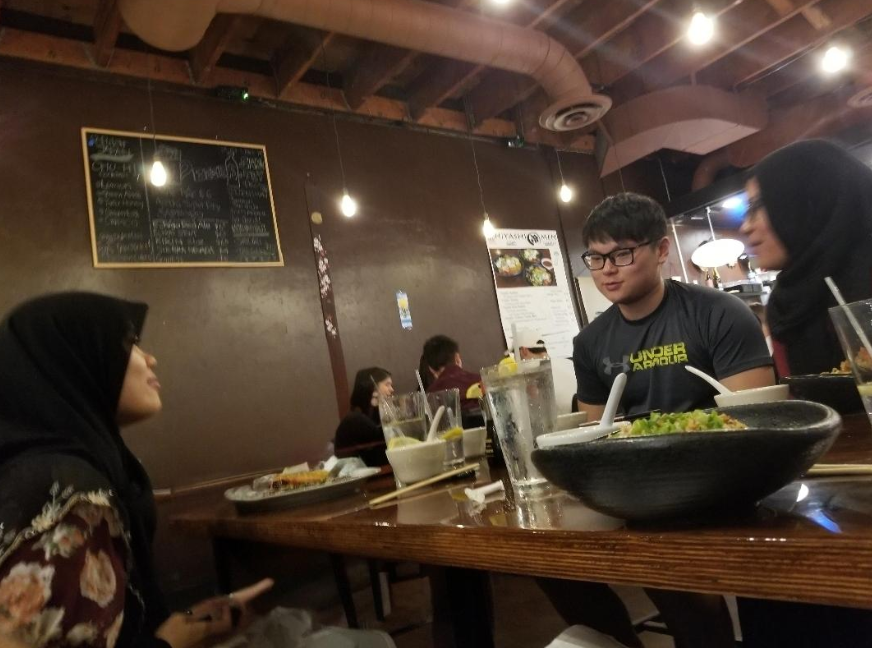 A group of friends eating at a table. Glasses of water littered throughout, with glass straws.